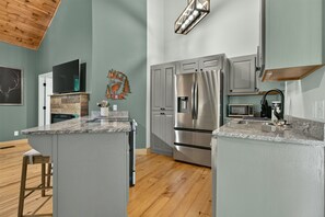 A modern kitchen with granite countertops, stainless steel appliances, and a wooden ceiling. - Gem of the Mountain -Cozy Cabin Retreat Near Helen (Sautee Nacoochee)