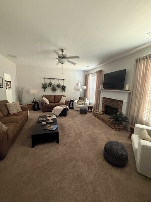 A living room with a ceiling fan, a fireplace, a television, and various seating arrangements. - The Launching Pad: Beautifully updated, swim-tennis community, great location! (Acworth)