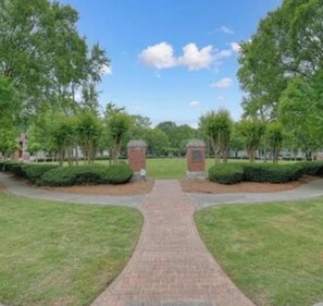 A paved pathway leading to a building entrance with brick pillars and a clear sky.