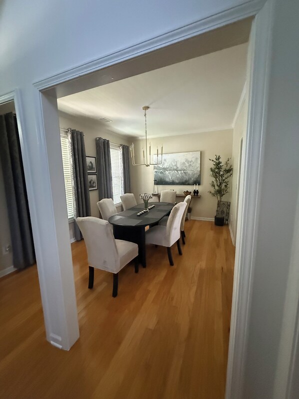 A dining area with a black table, white chairs, and a chandelier.