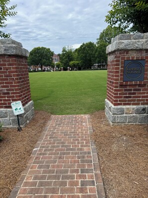 A brick pathway leading to a green lawn area with a sign indicating pet waste disposal. - The Launching Pad: Beautifully updated, swim-tennis community, great location! (Acworth)