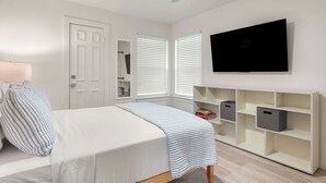 A bedroom with a bed, a ceiling fan, a TV mounted on the wall, and built-in storage units. - Vaulted Ceilings Home with 2,000-Book Library (Austin)