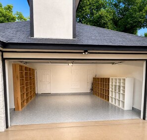 Eine Garage mit zwei weißen Türen, Holzregalen und einem Betonboden.