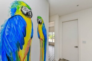 Una habitación con puerta y pared blanca, y ventana que da a vistas de vegetación.