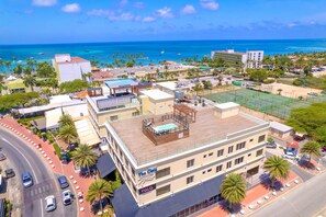 A coastal hotel with a rooftop pool, a tennis court, and a view of the ocean. - Ocean View 2BR, Palm Beach Strip (Noord)