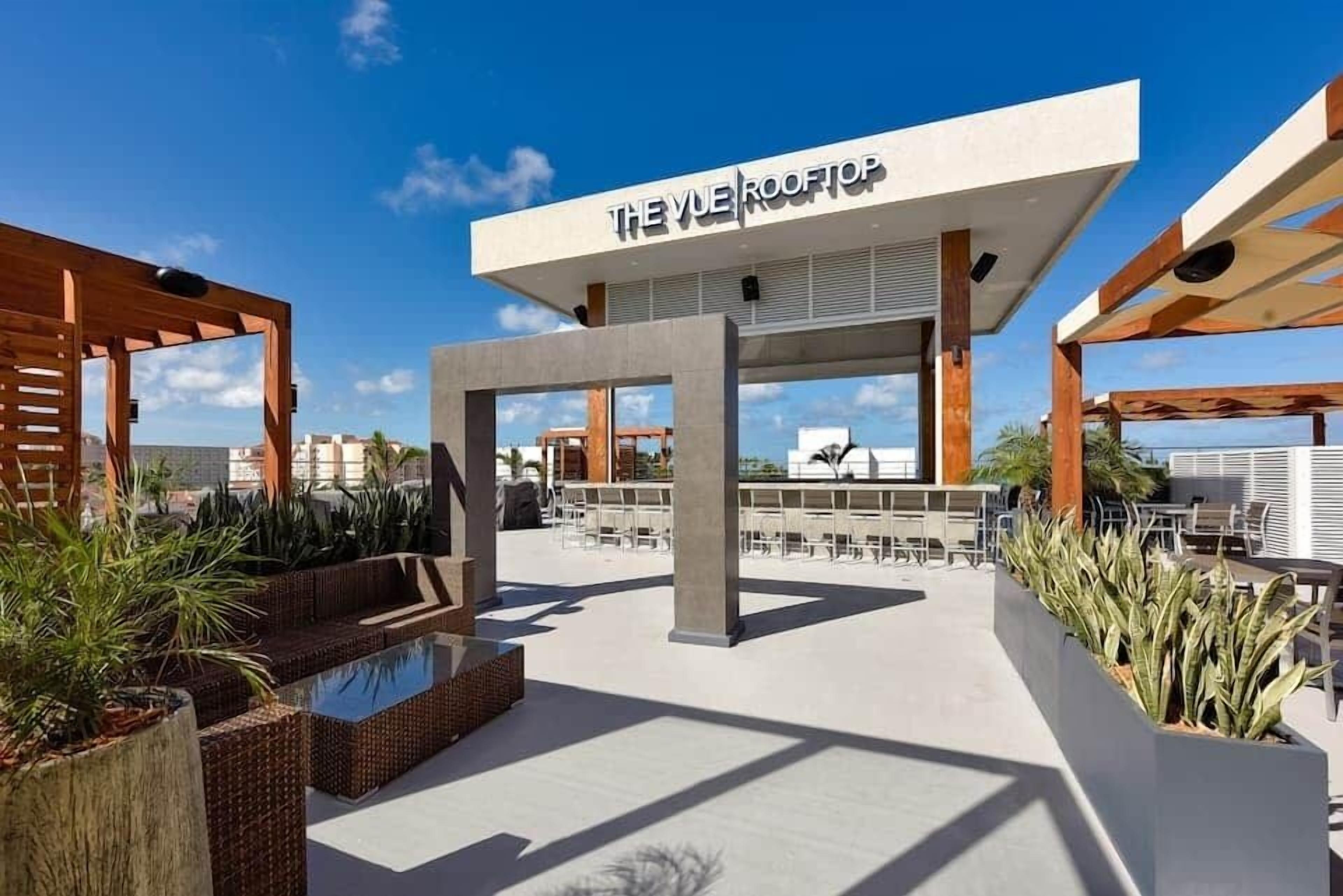Un espace bar situé sur le toit, avec des places assises en plein air et une piscine.