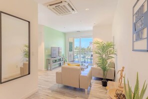 Una sala de estar moderna con un sofá, un televisor y un comedor con una mesa y sillas.