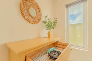 Ein Zimmer mit einem Holzkonsolentisch, einem Spiegel, einem Blumentopf und einem Fenster mit Blick.