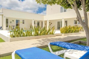 A modern building with a pool, lounge chairs, and potted plants. - Hideout Dream Big Suite- From Eagle Beach (Noord)