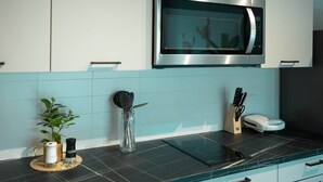 Una cocina con microondas, un bloque de cuchillos y una planta en la encimera.