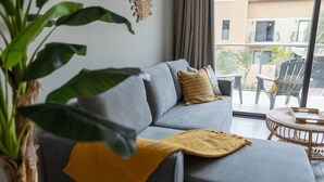 Un sofá gris con almohadones amarillos, una manta tejida y una planta en maceta.