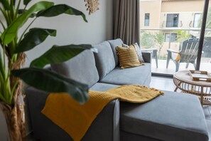Ein graues Sofa mit gelben Kissen, einer gewebten Decke und einem Blumentopf.