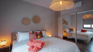 Habitación de hotel con una cama grande, una lámpara de noche, un espejo y una lámpara colgante de fibras.