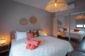 Ein Hotelzimmer mit einem großen Bett, einer Nachttischlampe, einem Spiegel und einer gewobenen Leuchte.