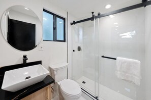 A modern bathroom with a glass-enclosed shower, a white toilet, and a large mirror above a black countertop sink. - Private 1Bd/1B Near Studios, Universal & Hollywood (Los Angeles County)