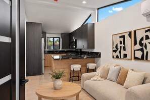 Open living area with a sofa, round coffee table and kitchen with two counter stools. - Private 1Bd/1B Near Studios, Universal & Hollywood (Los Angeles County)