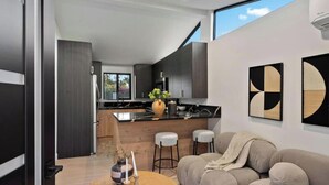 Una cocina moderna con armarios oscuros, una isla central y taburetes de bar.