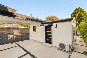 A modern residential building with a garage, a black sliding door, and an air conditioning unit. - Private 1Bd/1B Near Studios, Universal & Hollywood (Los Angeles County)