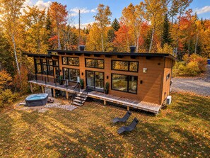 A modern cabin with a deck, hot tub, and outdoor seating. - Le Clorane | spa | relax (Matawinie Regional County Municipality)