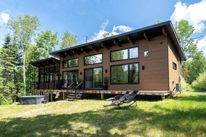 Ein modernes, zweistöckiges Haus mit Terrasse, großen Fenstern und einem Rasen.