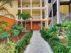 A multi-story building with a central courtyard, a staircase, and a yellow exterior wall. - Amazing 2-bedroom condo in peaceful Kissimmee with AC and gym (Kissimmee)