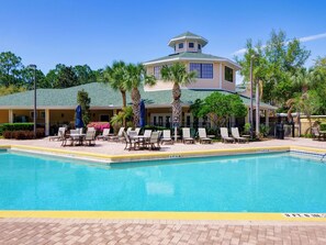 A hotel with a swimming pool, lounge chairs, palm trees, and a covered patio area. - Amazing 2-bedroom condo in peaceful Kissimmee with AC and gym (Kissimmee)