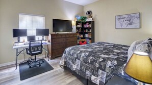 Ein Schlafzimmer mit einem Bett, einem Schreibtisch, einem Computerarbeitsplatz und einem Bücherregal.