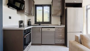 Een kleine keuken met een magnetron, koffiezetapparaat, oven, vaatwasser en een koelkast.