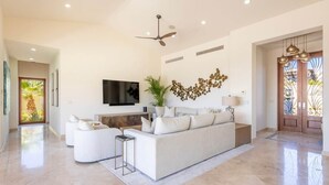 Ein geräumiges Wohnzimmer mit einer großen Couch, einem Flachbildfernseher und einem Deckenventilator.
