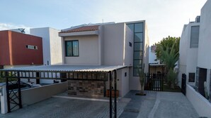 Un edificio moderno con un portico coperto, un muro in piastrelle e un cancello in metallo.