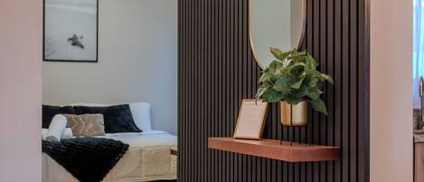 Una hall moderna di un hotel con un pannello a parete in legno, un grande specchio, una pianta in vaso e un quadro incorniciato.