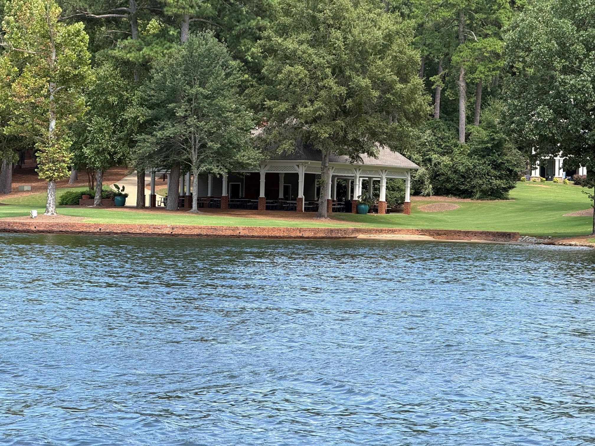 A lakeside pavilion with outdoor seating and a view of the water.