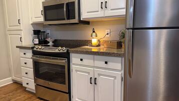 A kitchen with white cabinetry, stainless steel appliances, a granite countertop, and a built-in oven.