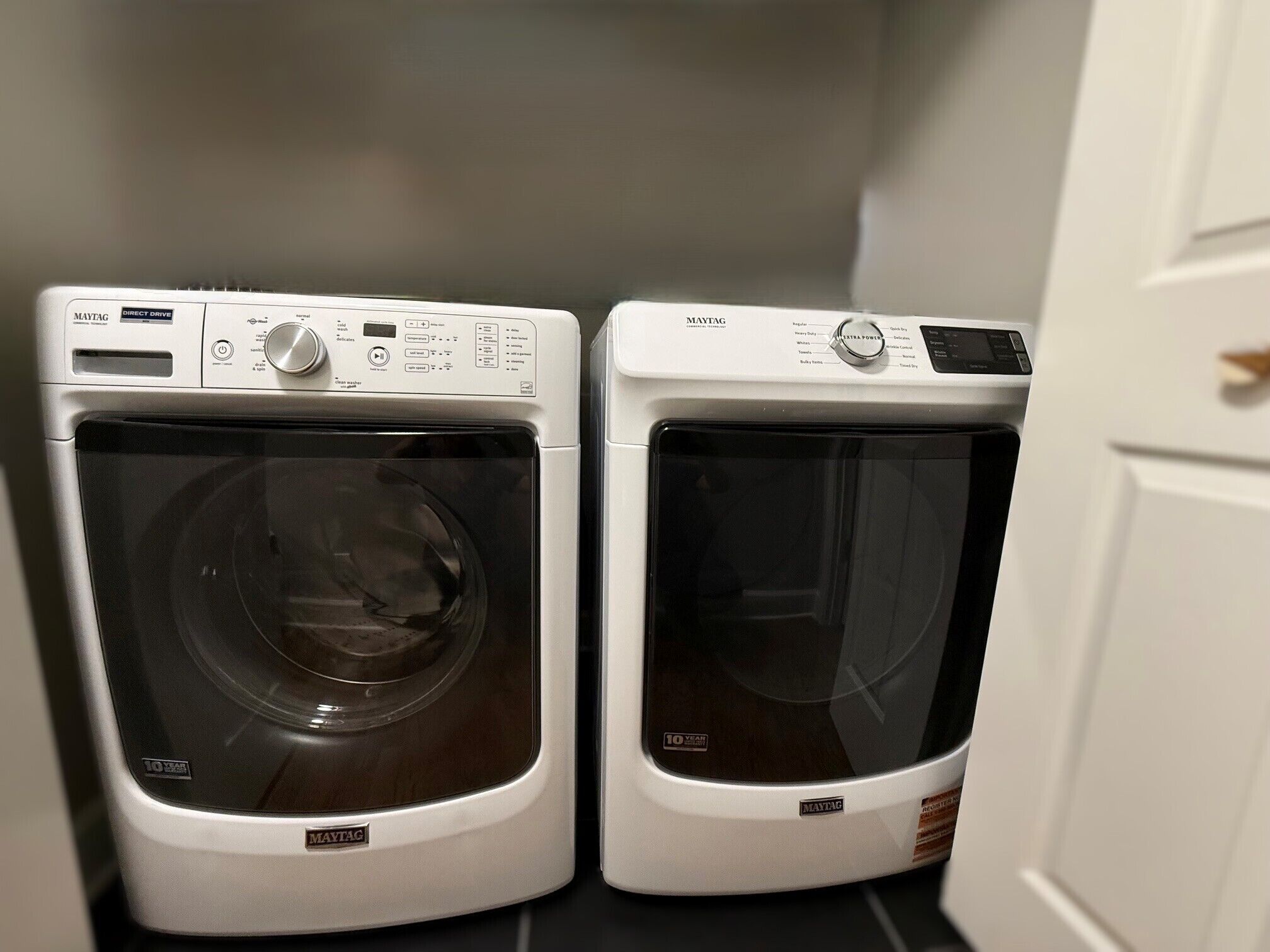 Two Maytag front-loading washing machines in a laundry room.
