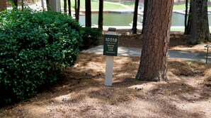 A signpost with the text '1031B Marina Cove Lane (downstairs)' in a landscaped area with trees and a grassy background. - NEW LISTING Lake View In Reynolds on Oconee, 2bd/2bath Fully Remodeled Sleeps 6 (Greensboro)