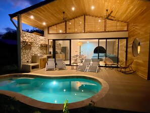 Ett modernt hus med en swimmingpool, solstolar och en matplats.