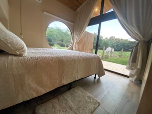 Ein Schlafzimmer mit einem großen Bett, einem Rundfenster und Blick ins Freie.