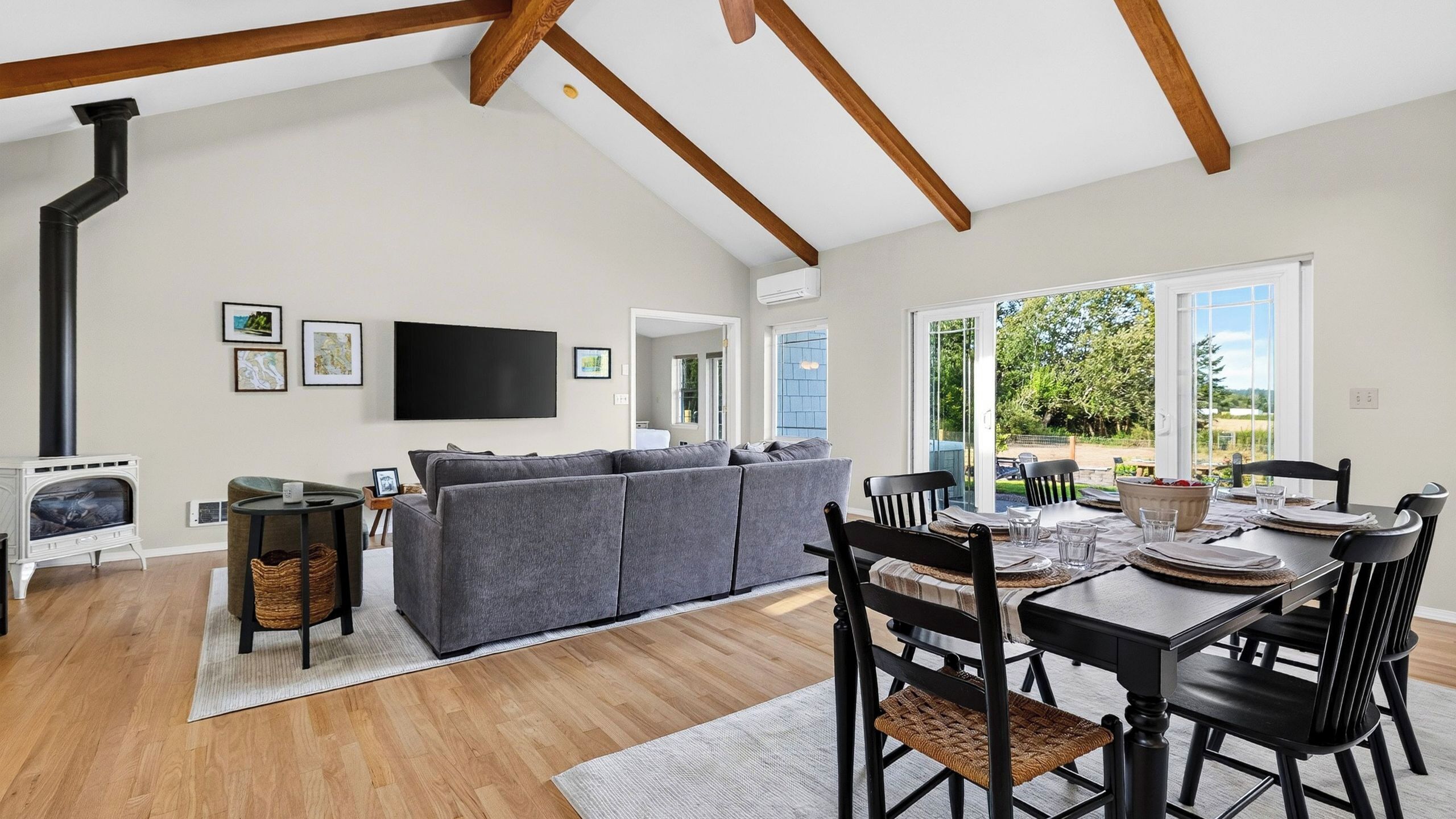 A spacious living area with a fireplace, sofa, dining table, and chairs.