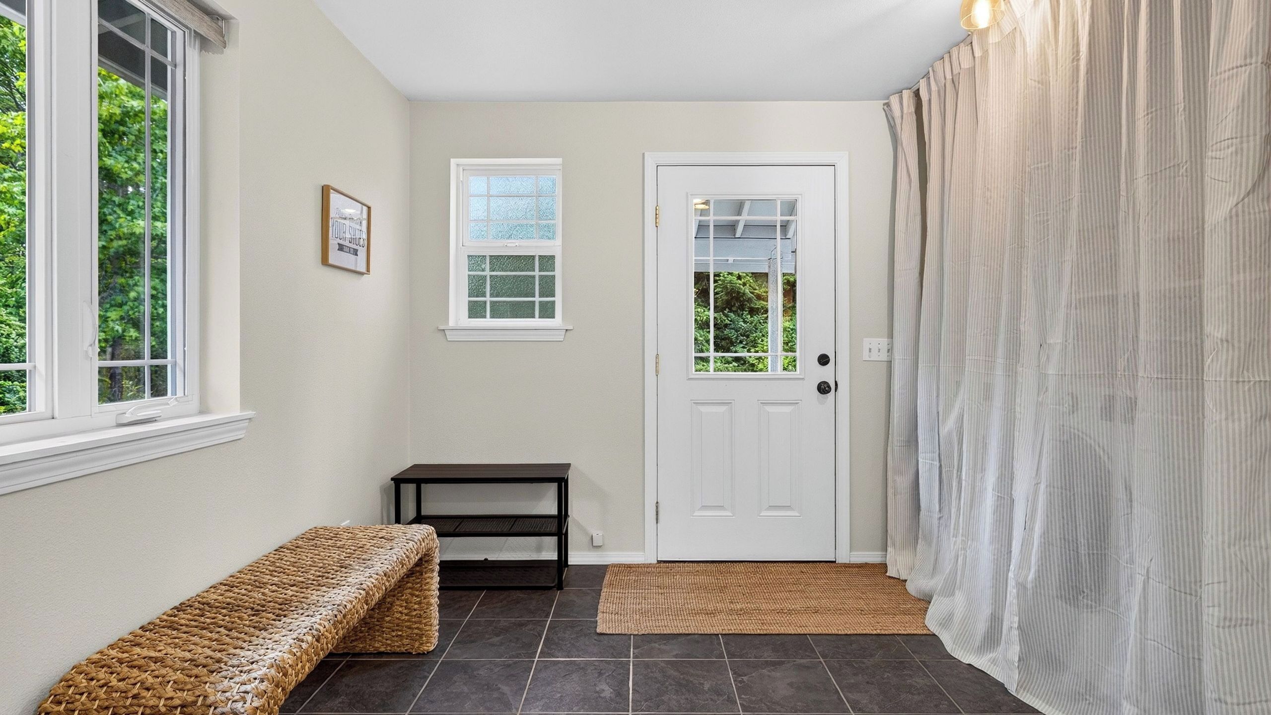 A hallway with a bench, a door, a small table, and a window.