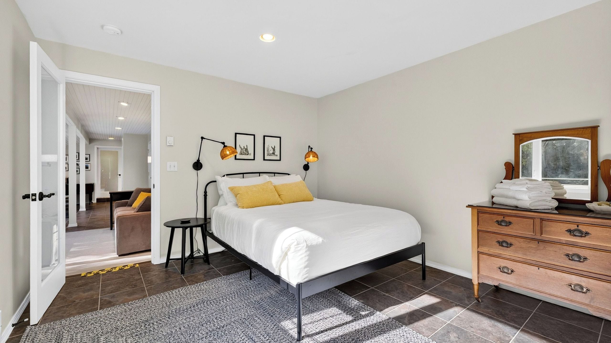 A bedroom with a bed, bedside lamps, a dresser, and a mirror.