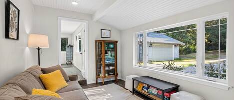 A living room with a sofa, a lamp, a bookshelf, and a view of a garage.