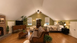A loft-style room with a fireplace, a sofa, a bed, and a television. - The Good Neighbor’s Loft (Orrstown)