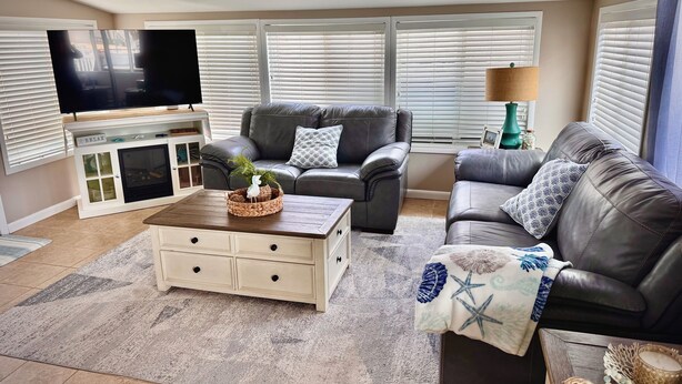 A living room with a television, two leather sofas, a coffee table, and a fireplace. - Mystic Island Lagoon Front Escape with Private Dock and Hot Tub ⚓️☀️ (Little Egg Harbor Township)