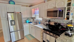 A kitchen with white cabinets, a stainless steel refrigerator, a microwave, an oven, and a sink. - Mystic Island Lagoon Front Escape with Private Dock and Hot Tub ⚓️☀️ (Little Egg Harbor Township)