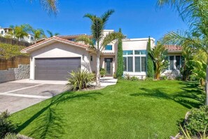 A two-story house with a garage, a well-maintained lawn, and various plants. - Luxury Coastal Retreat - Beach & Lagoon (Carlsbad)
