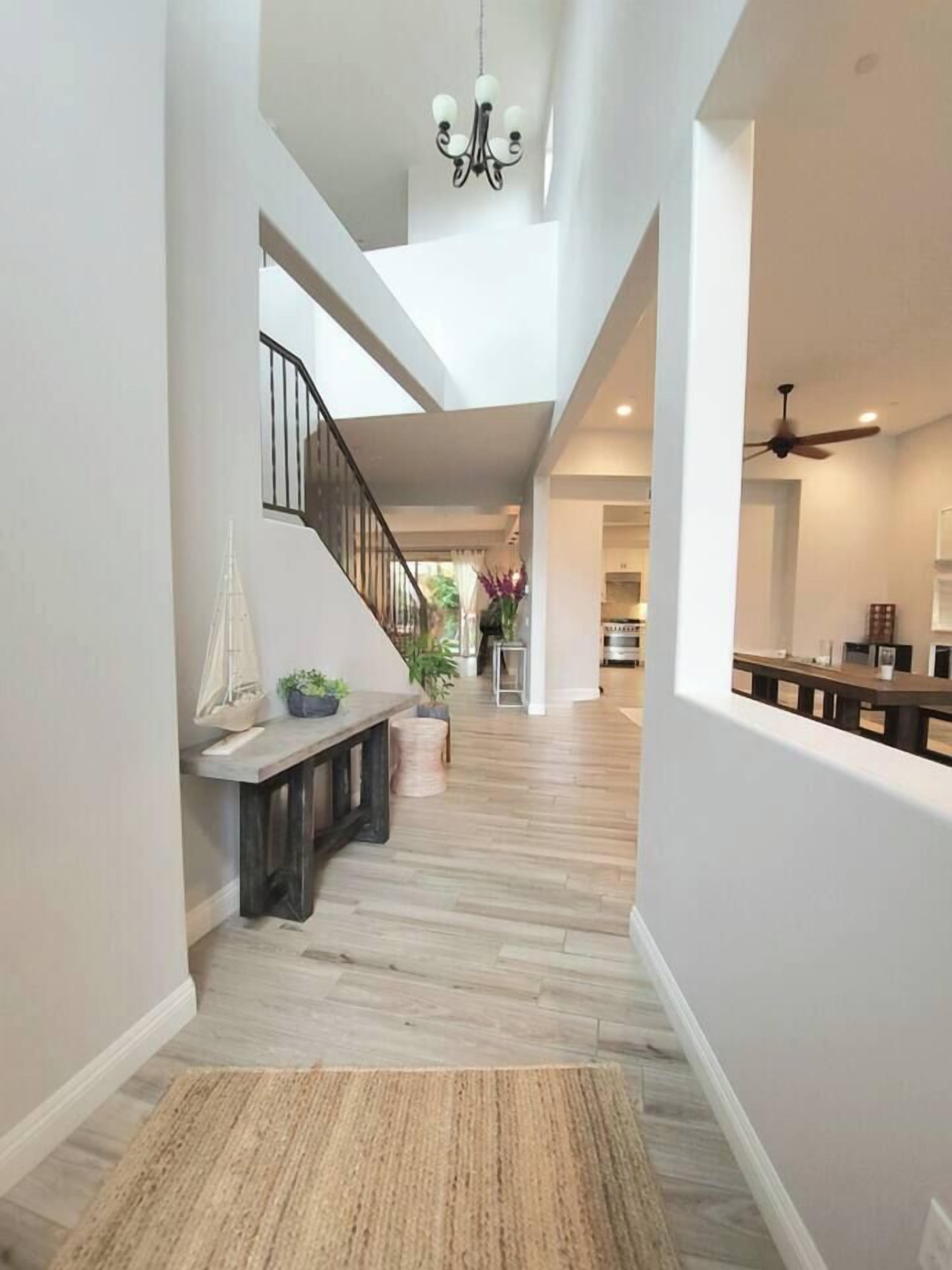 A spacious hallway with a wooden bench, a staircase, and a ceiling fan.