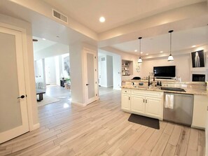 A spacious kitchen with white cabinetry, a large island, and pendant lighting. - Luxury Coastal Retreat - Beach & Lagoon (Carlsbad)