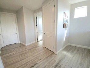 Une pièce avec un plancher en bois, des murs blancs et une porte qui donne sur une autre pièce.
