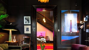 A modern interior with a chandelier, a sofa, a coffee table, and a large painting on the wall. - Truitt Hotel (St. Louis)