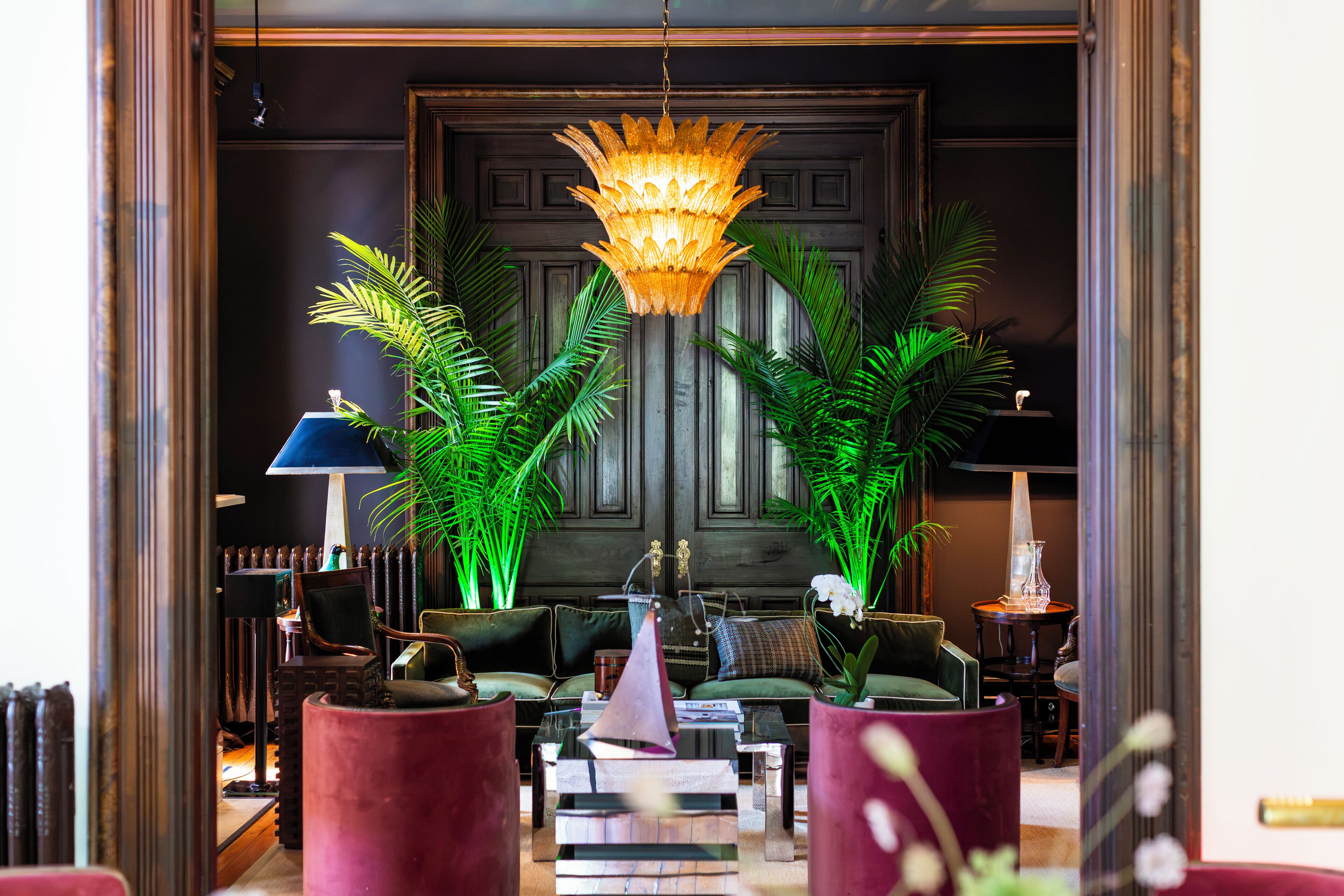 A well-lit lobby with a chandelier, seating area, and decorative plants.